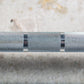 Gray knurled Olympic barbell with black grip bands, close-up detail on textured surface