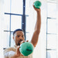 Man holding green Aeromat mini weight balls, one in each hand, demonstrating exercise use by bright window