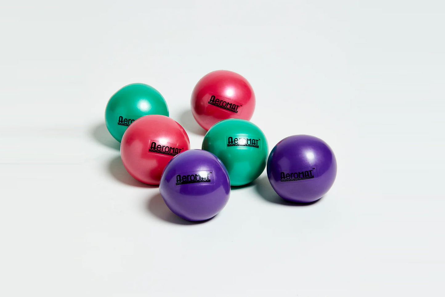 Set of five Aeromat mini weight balls in pink, purple, and teal with glossy finish on white background