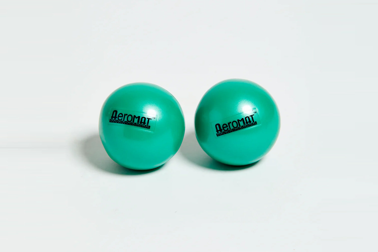 Pair of turquoise Aeromat mini weight balls with black branding, on white background