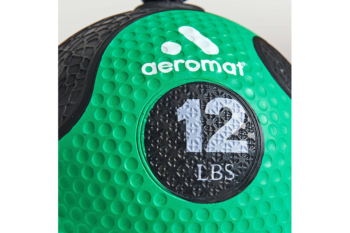 Aeromat 12 lbs green medicine ball with textured grip and black rope handles on white background
