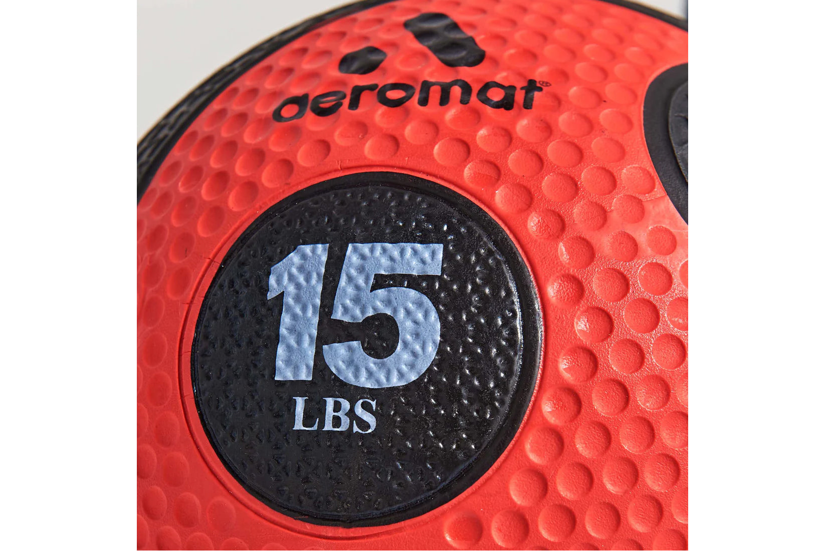 Aeromat 15 LBS red textured medicine ball with black weight label, close-up detail view
