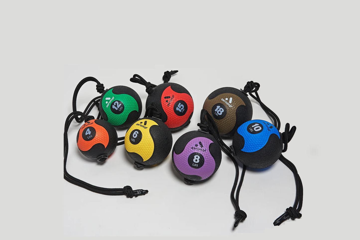 Set of seven medicine balls with rope handles in assorted colors including orange, green, red, yellow, purple, brown, and blu