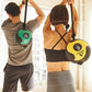 Two people holding green and yellow medicine balls with black rope handles during an overhead exercise