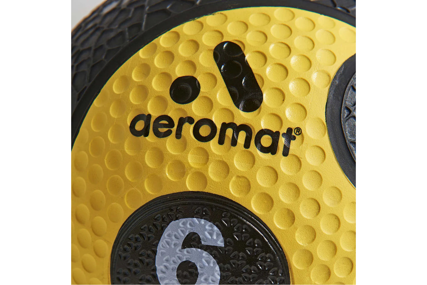 Aeromat yellow medicine ball with textured grip pattern and black branding detail, close-up view