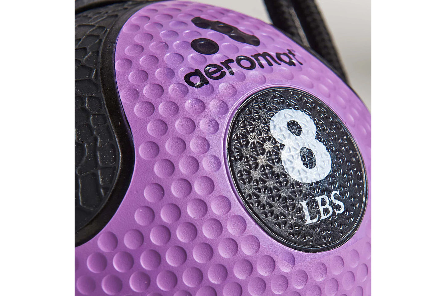 Purple textured medicine ball with black handles, featuring weight marking and Aeromat branding on dimpled surface