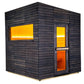 Black wood sauna cabin with yellow and orange interior lighting, featuring horizontal siding, large window, and solid door on