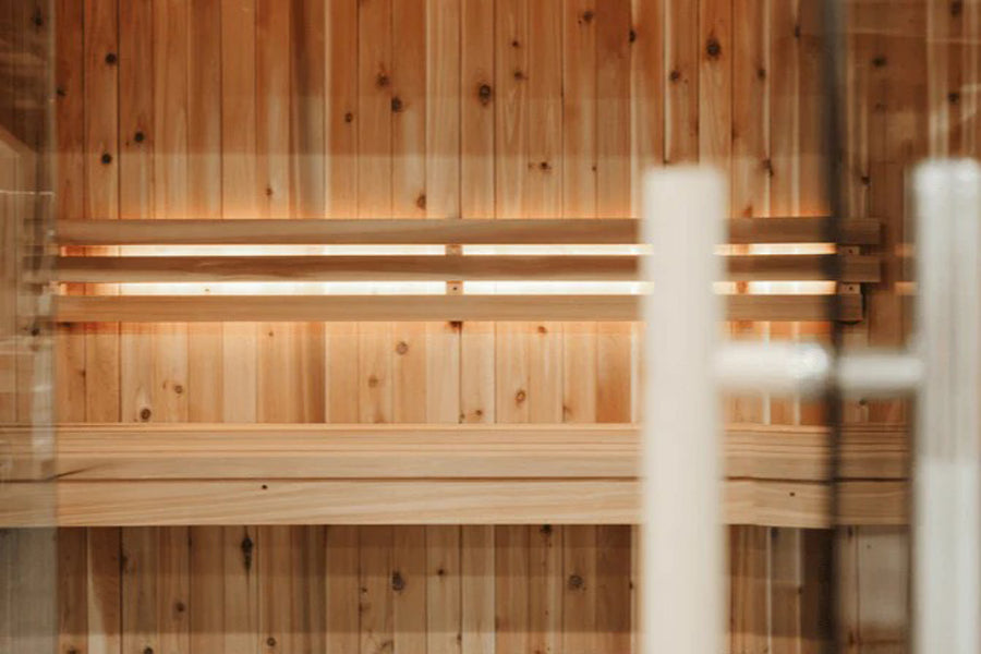 Interior view of wooden sauna with light wood paneling, built-in bench seating, and ambient lighting on white background