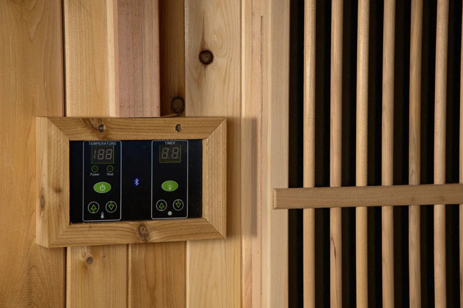 Digital control panel with dual temperature displays mounted in light wood frame on wooden sauna wall