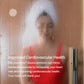 Woman in white towel wrap and red swimsuit visible through glass sauna door, representing sauna wellness experience