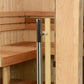 Sauna door detail showing stainless steel and black handle on light wood frame with interior wooden benches visible