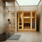 Cedar wood sauna with glass door and side panels next to frameless glass shower enclosure in modern bathroom with skylight