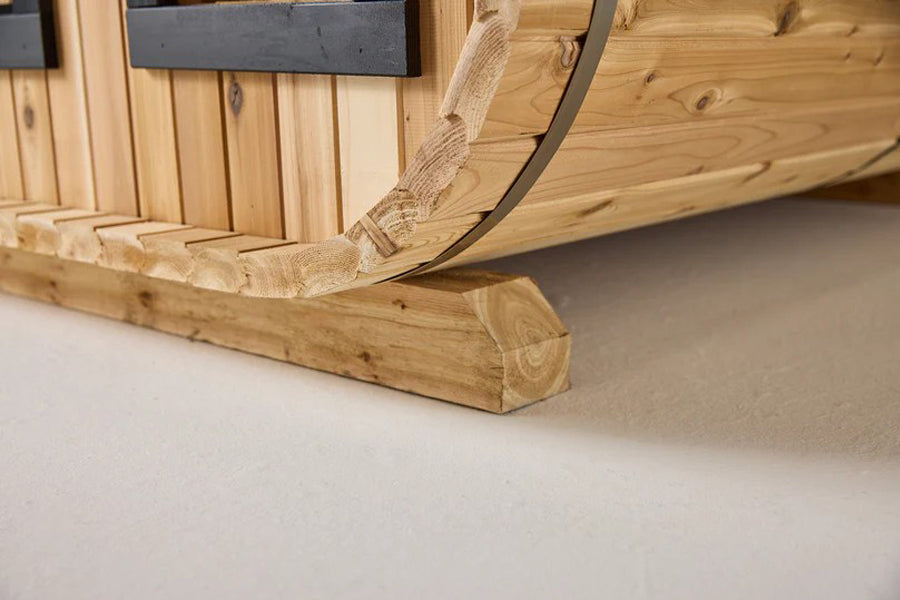 Wooden sauna base and curved metal band detail on white background, showing natural wood grain and construction