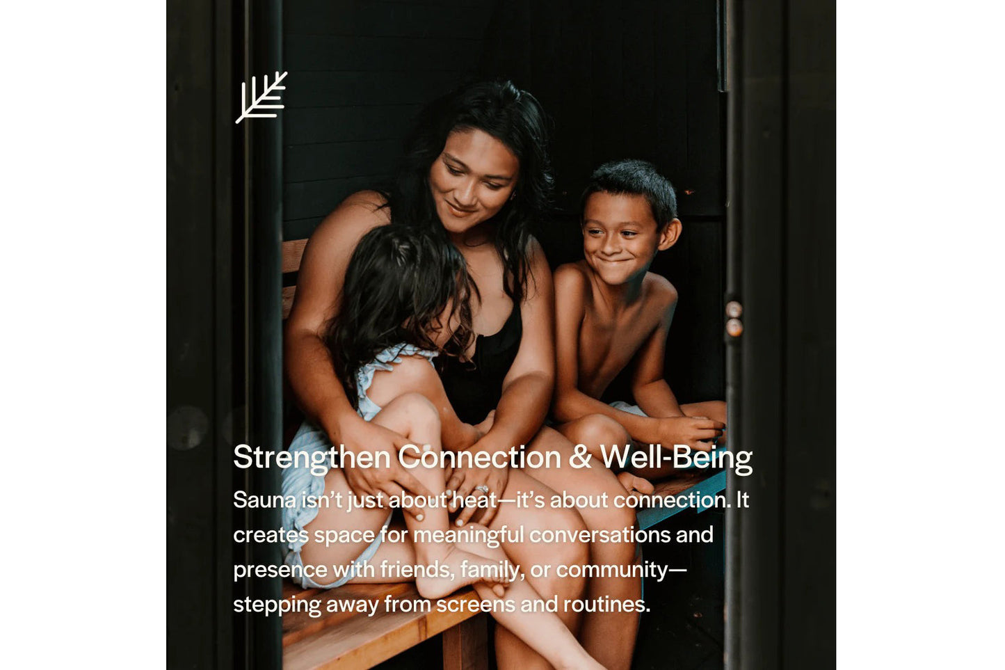 Woman and two children sitting together inside wooden sauna with dark interior walls