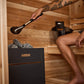 Harvia sauna heater with ladle being used to pour water over stones in wooden sauna interior