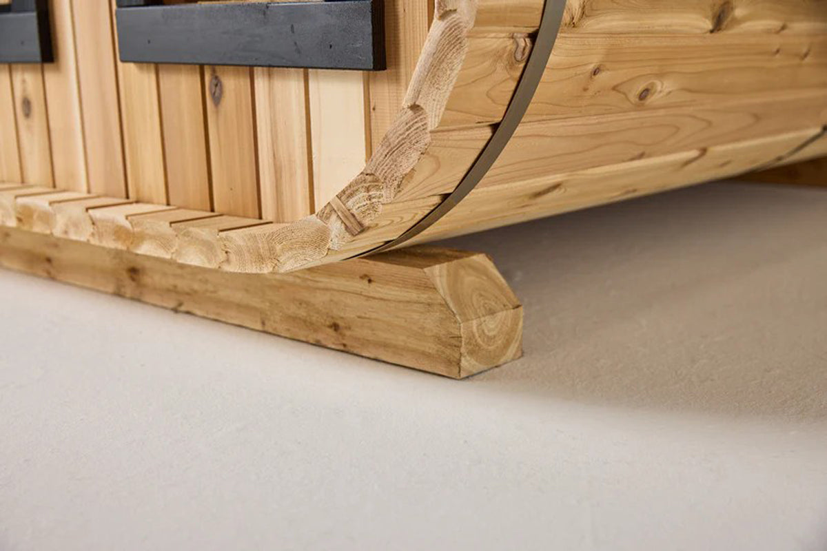 Natural wood sauna interior showing curved cedar walls and wooden bench seating detail on neutral background