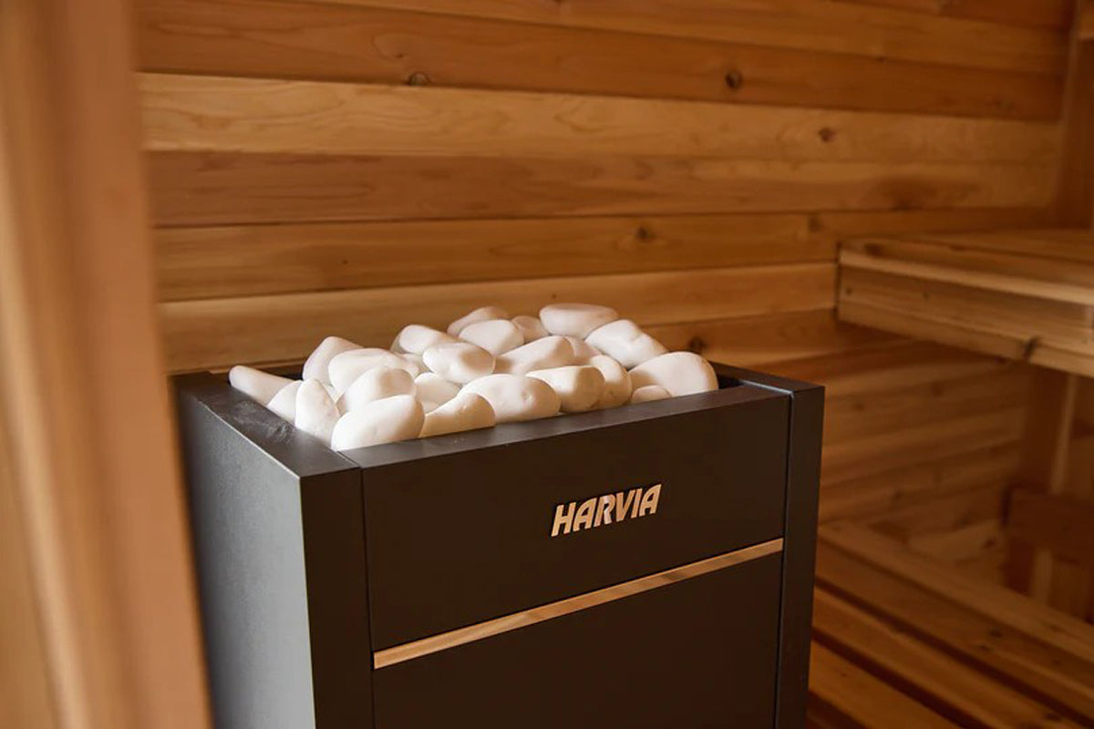 Harvia black sauna heater with white stones on top, positioned in wooden sauna room with benches