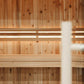 Interior view of wooden sauna with cedar wall paneling, horizontal bench seating, and infrared light strips mounted on upper 