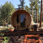 Almost Heaven Charleston 4-person barrel sauna with wooden exterior and glass door in forest setting