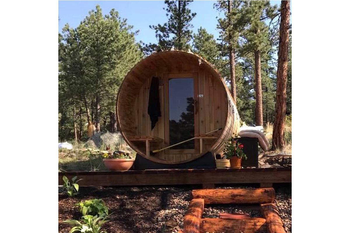 Almost Heaven Charleston 4-person barrel sauna with wooden exterior and glass door in forest setting