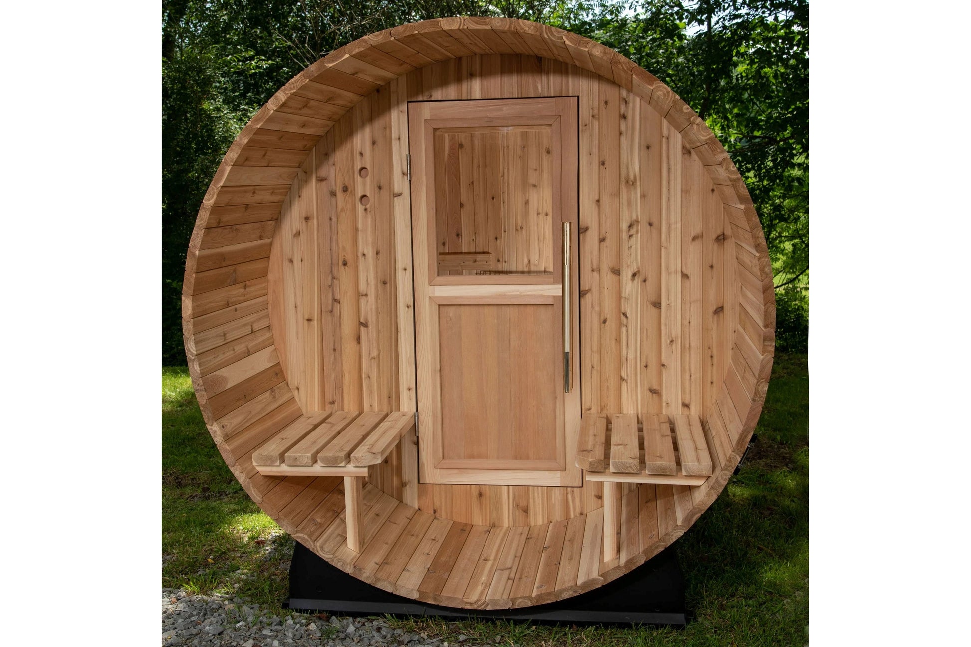 Cylindrical barrel sauna made of light cedar wood with arched roof, wooden door with window, and bench seating visible inside