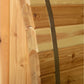 Natural wood barrel sauna corner detail showing rounded cedar logs and metal band, on white background