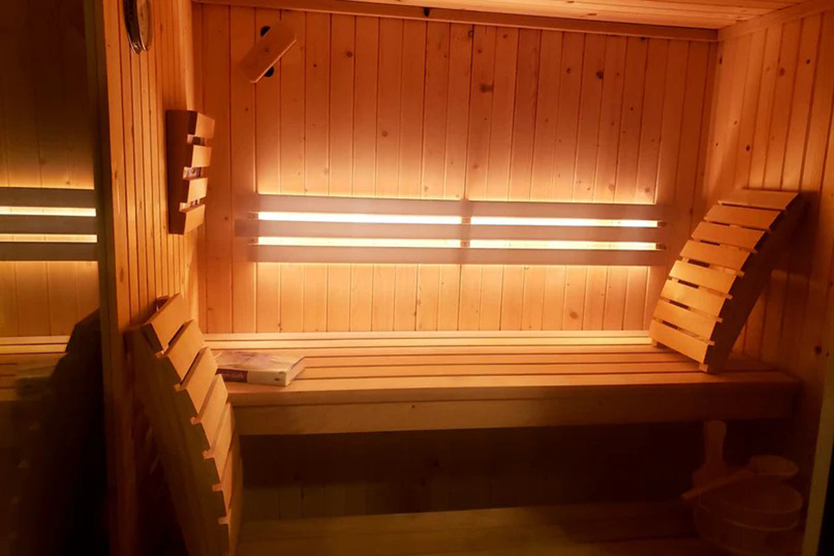 Almost Heaven Grayson 4-person indoor sauna with light pine wood interior, built-in benches, infrared heating strips, and gla