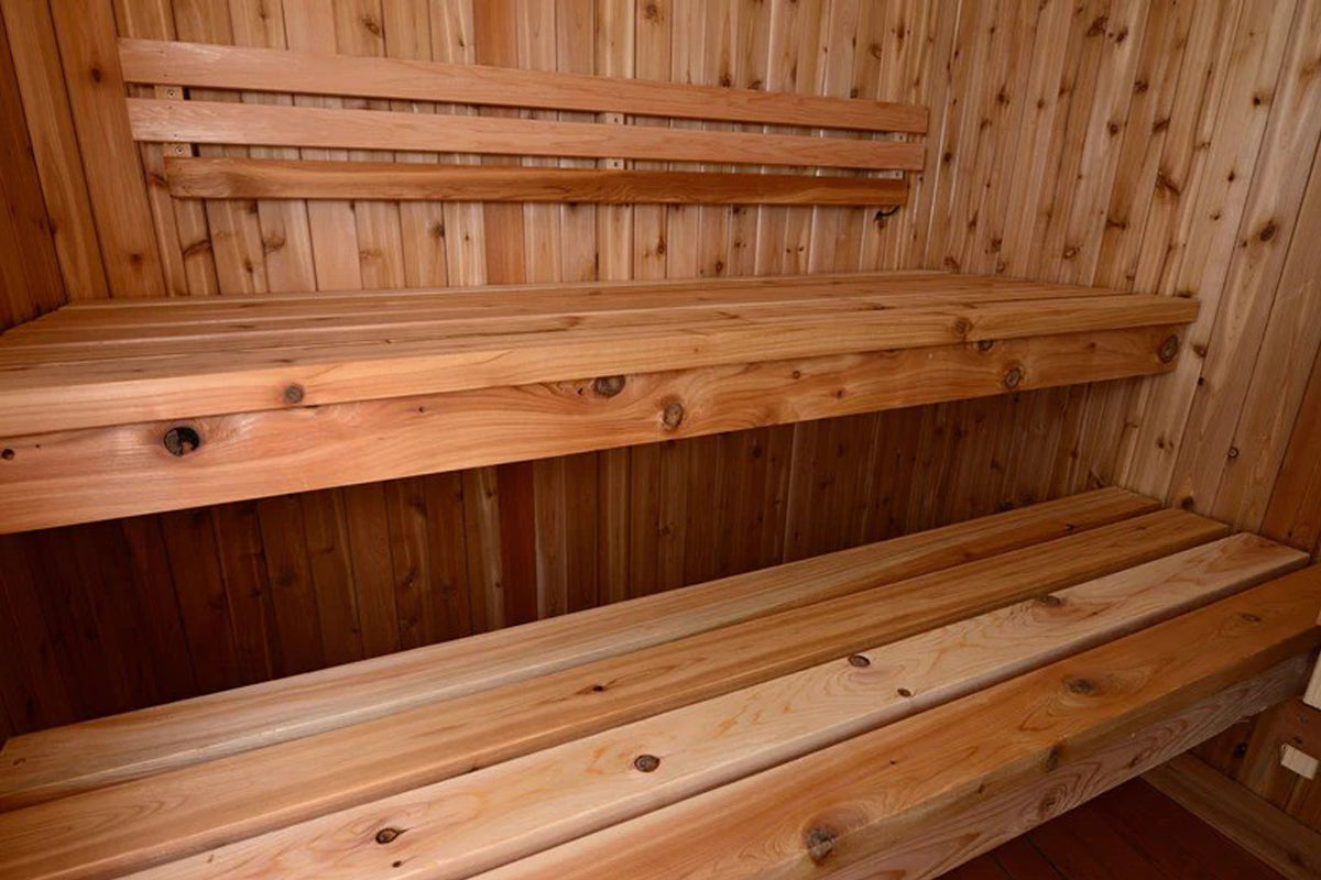 Cedar wood sauna interior with tiered wooden benches and backrest rails, flat lay view