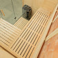 Interior view of wooden sauna with light wood slats, glass door, stainless steel heater, and brick walls