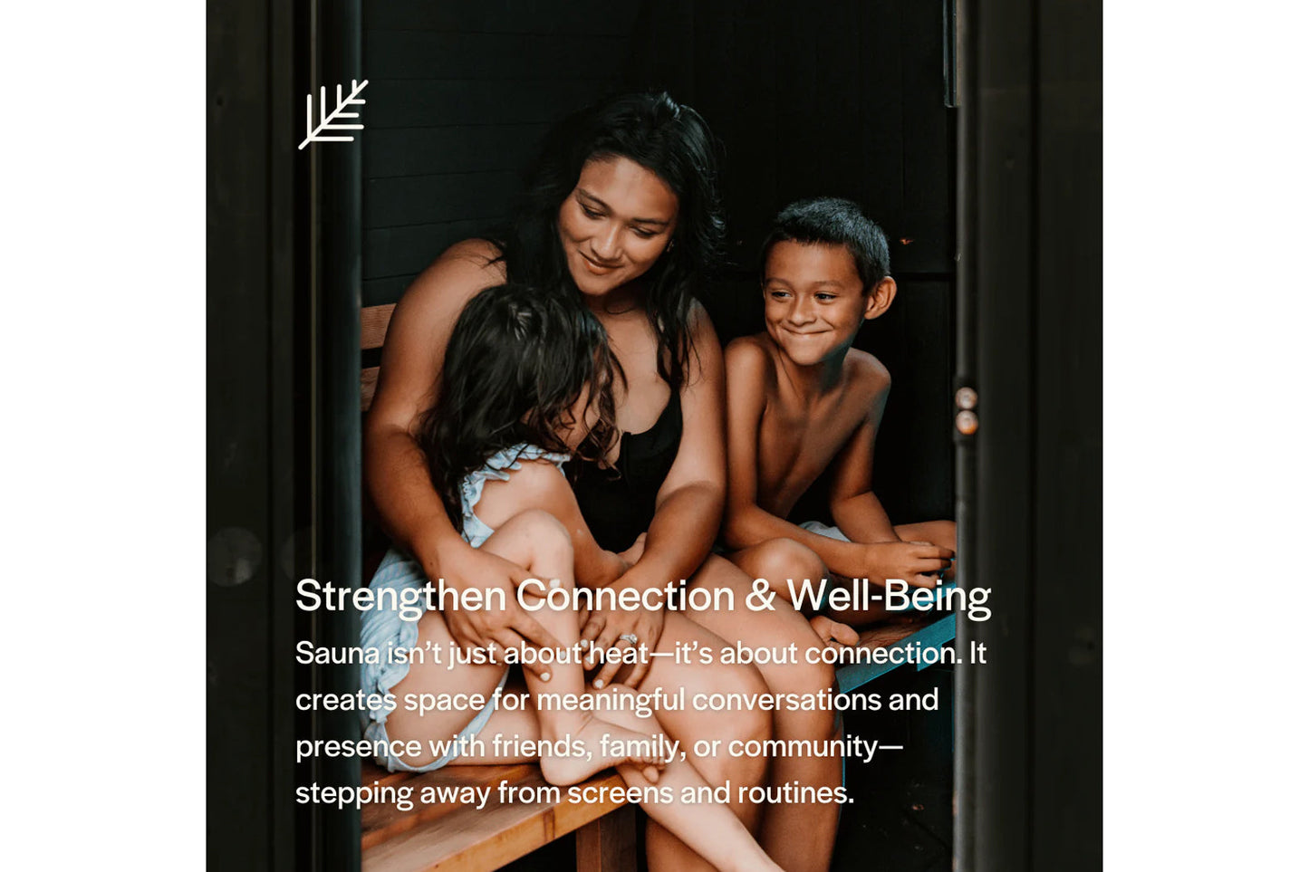 Woman and two children smiling together inside wooden sauna with dark interior walls