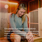Woman wearing gray t-shirt sitting in wooden infrared sauna with warm orange lighting
