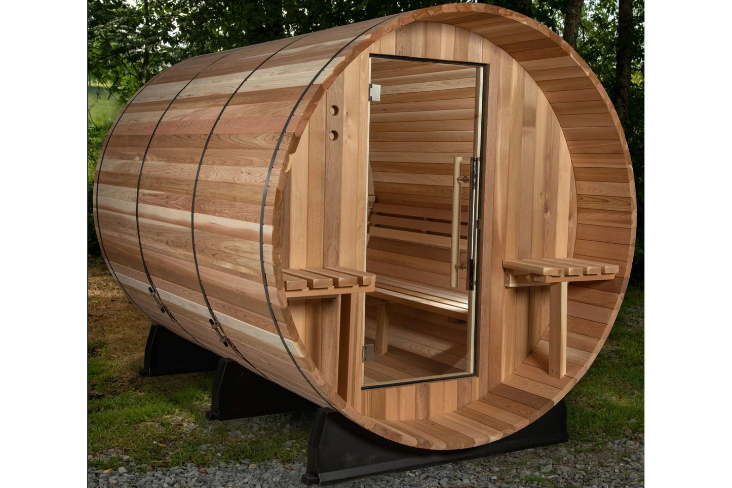 Wooden barrel sauna with cedar construction, open glass door, benches visible inside, metal bands around exterior, on black m