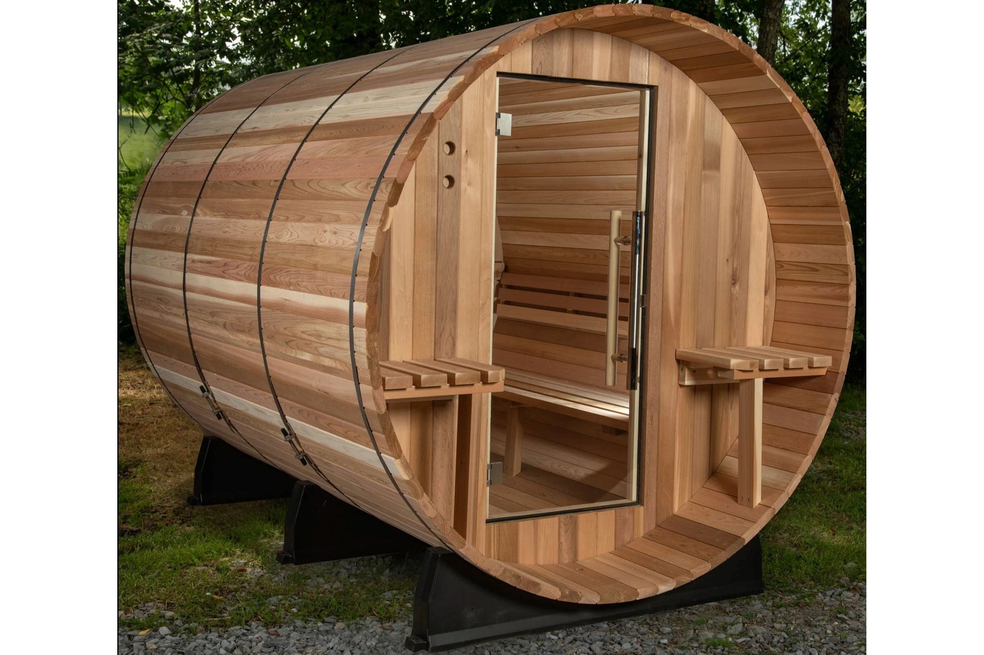 Wooden barrel sauna with cedar construction, open glass door, benches visible inside, metal bands around exterior, on black m