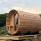 Barrel sauna with natural wood construction and curved cylindrical design, mounted on wooden platform in garden setting