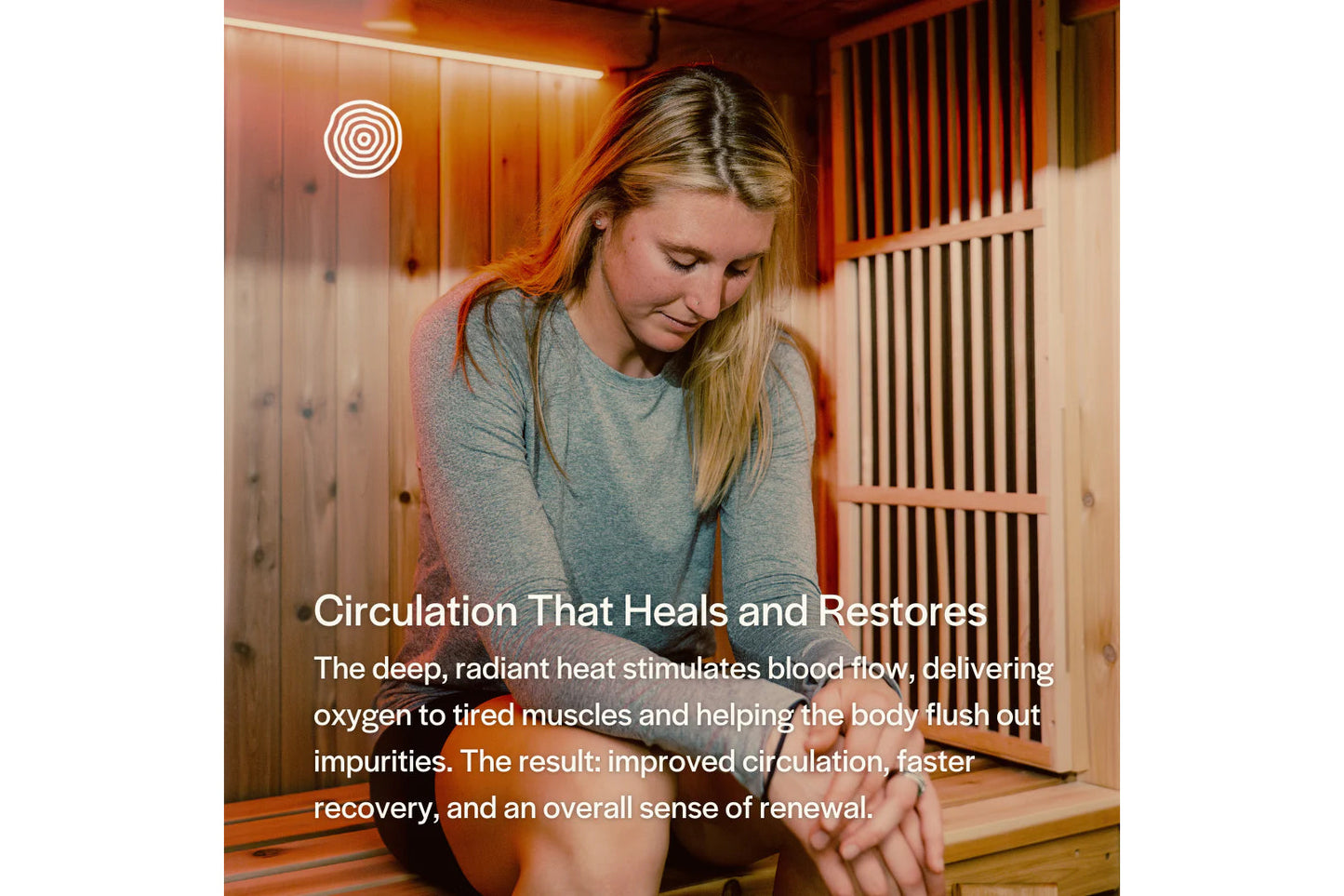 Woman in gray t-shirt sitting in wooden infrared sauna with warm orange lighting, relaxation wellness environment
