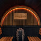 Modern barrel sauna interior with wooden benches on sides, arched wooden ceiling with vertical slats, orange neon lighting, s