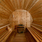 Interior of wooden barrel sauna with benches on both sides, arched ceiling, and heater stove at far end