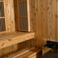 Cedar wood hybrid sauna interior with vertical shiplap walls, wooden benches with knots, slatted vents, and Harvia heater vis