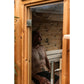 Man sitting inside wooden barrel sauna with glass window and wood interior, viewed through open door