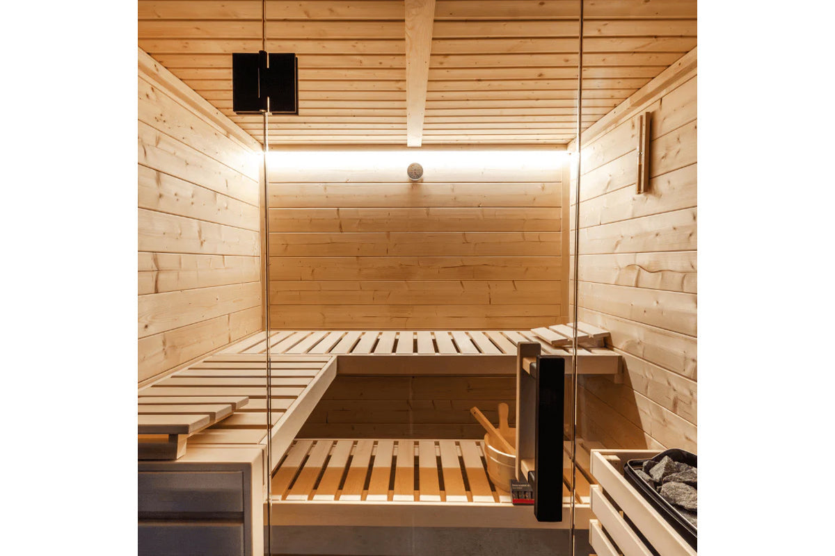 Almost Heaven Nordik indoor sauna with light wood interior, tiered benches, glass door, and heater visible on right side