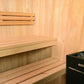 Almost Heaven Oasis 4-person indoor sauna with light wood interior, tiered benches, and black Harvia heater with stones visib