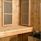 Natural wood sauna interior with two hinged glass doors featuring vertical slats, wooden bench seating, and heater visible in
