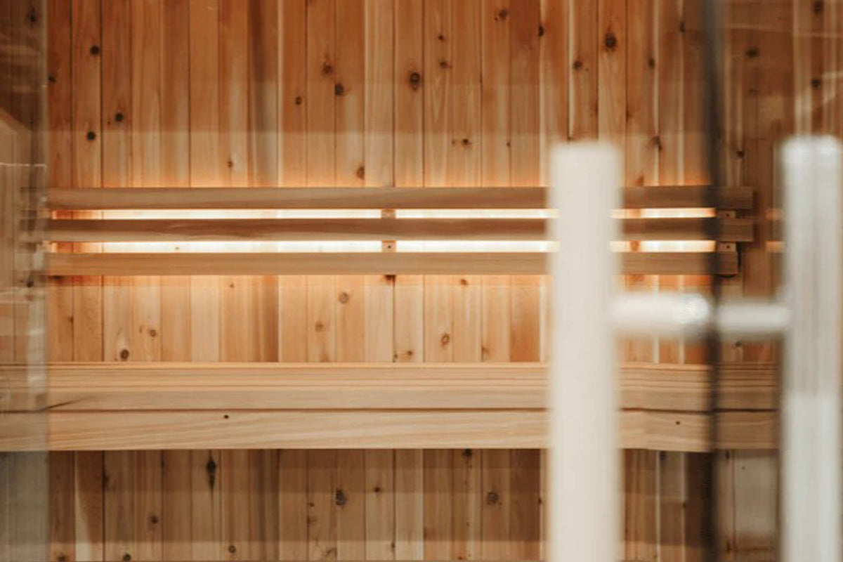 Cedar wood sauna interior with wooden bench seating and built-in lighting strips mounted on walls