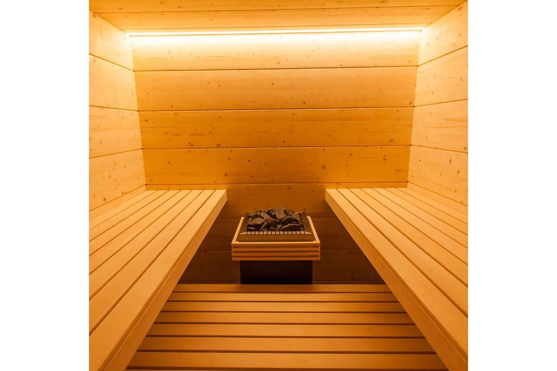 Interior of wooden sauna with benches on both sides, heated rocks, and overhead lighting