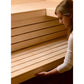 Woman in white long-sleeve shirt examining interior wooden benches of Almost Heaven Patterson corner sauna