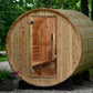 Cylindrical wooden barrel sauna with open door revealing cedar interior, benches, and ventilation, positioned in landscaped y