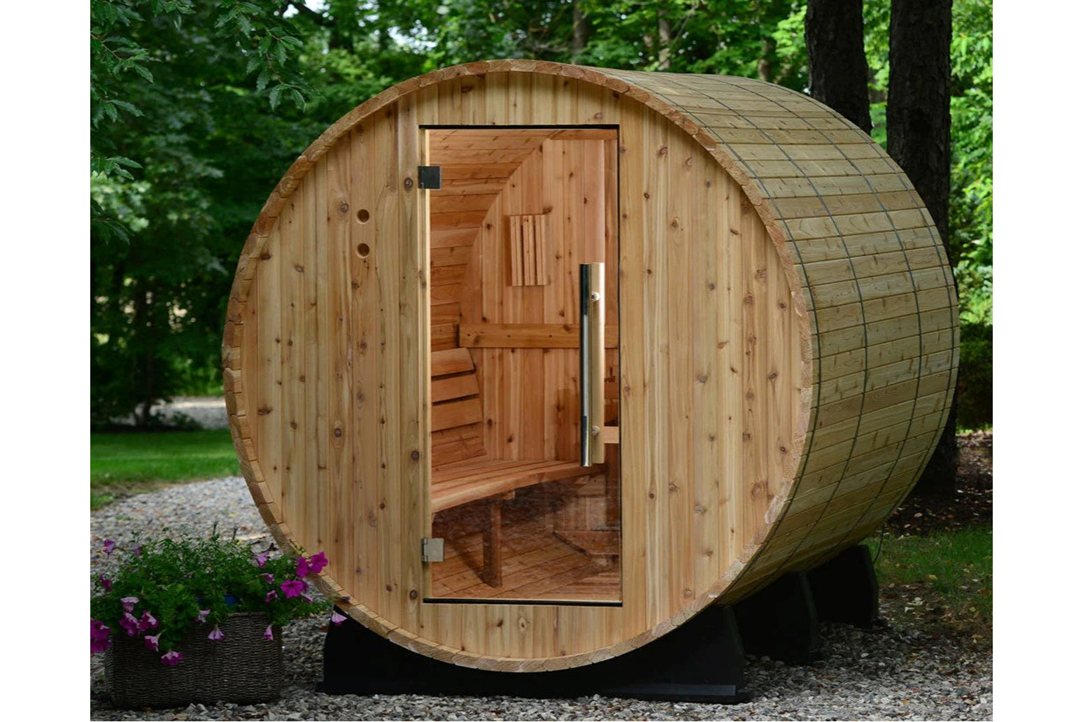 Cylindrical wooden barrel sauna with open door revealing cedar interior, benches, and ventilation, positioned in landscaped y