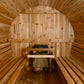 Interior view of barrel sauna with light wood construction, curved ceiling, wooden benches on both sides, and sauna heater wi