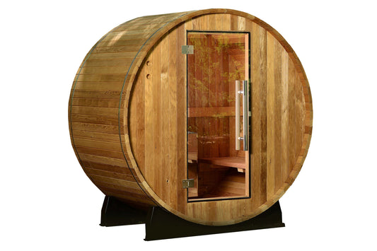 Cylindrical wooden barrel sauna with glass door, cedar construction, and metal bands, on black support stand against white ba