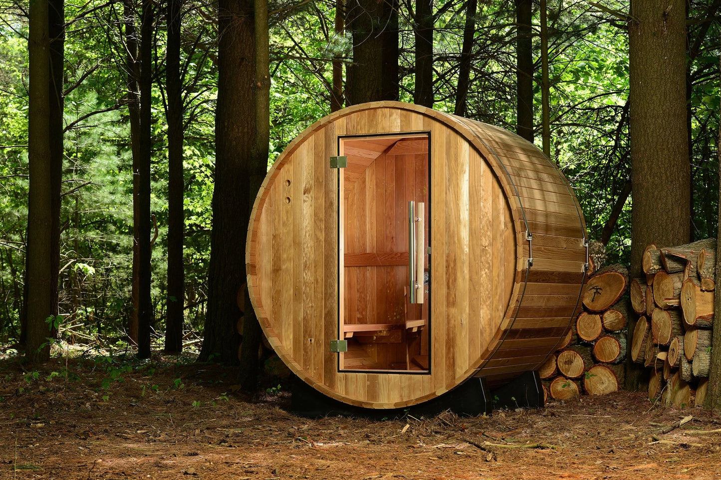 Cylindrical wooden barrel sauna with natural wood exterior and open wooden door showing interior, in forest setting with stac